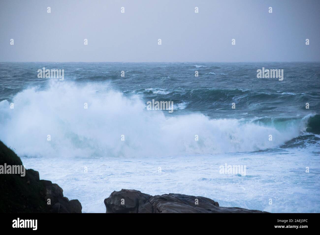 Grandi onde si infrangono e spruzzi contro le rocce Foto Stock