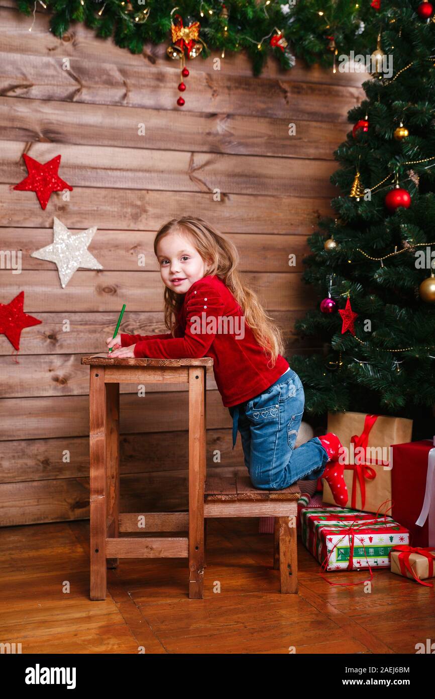 Carino piccolo bambino ragazza scrive la lettera a Santa a casa Foto Stock