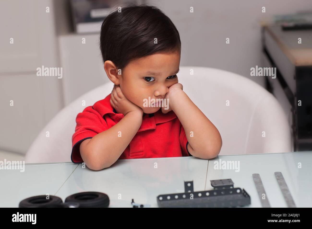 Un bambino guardando sconvolto o frustrato durante il tentativo di costruire un difficile da assemblare giocattolo che è in pezzi. Foto Stock