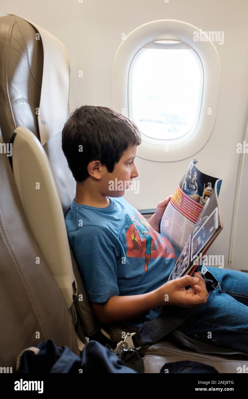 Ragazzo, di età 7-8 leggendo una rivista in aereo Foto Stock