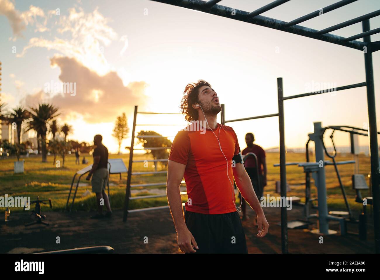 Giovane sportivo da uomo con gli auricolari nelle orecchie guardando il Monkey bar per fare esercizio in palestra park - Uomo motivare se stesso a fare esercizi Foto Stock