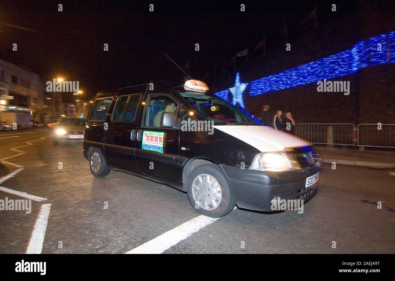 Taxi rendendo il suo modo attraverso le strade di Cardiff, Regno Unito durante il periodo di Natale. Foto Stock