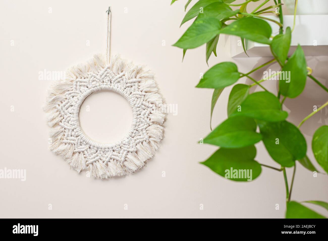 Cotone artigianali macrame mandala decorazione murale appeso a una parete con foglie di colore verde Foto Stock