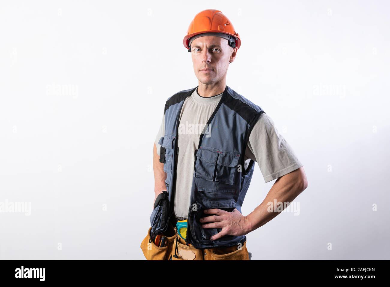 Il builder mettere le mani sui suoi fianchi. In abiti da lavoro e di elmetto. Foto Stock
