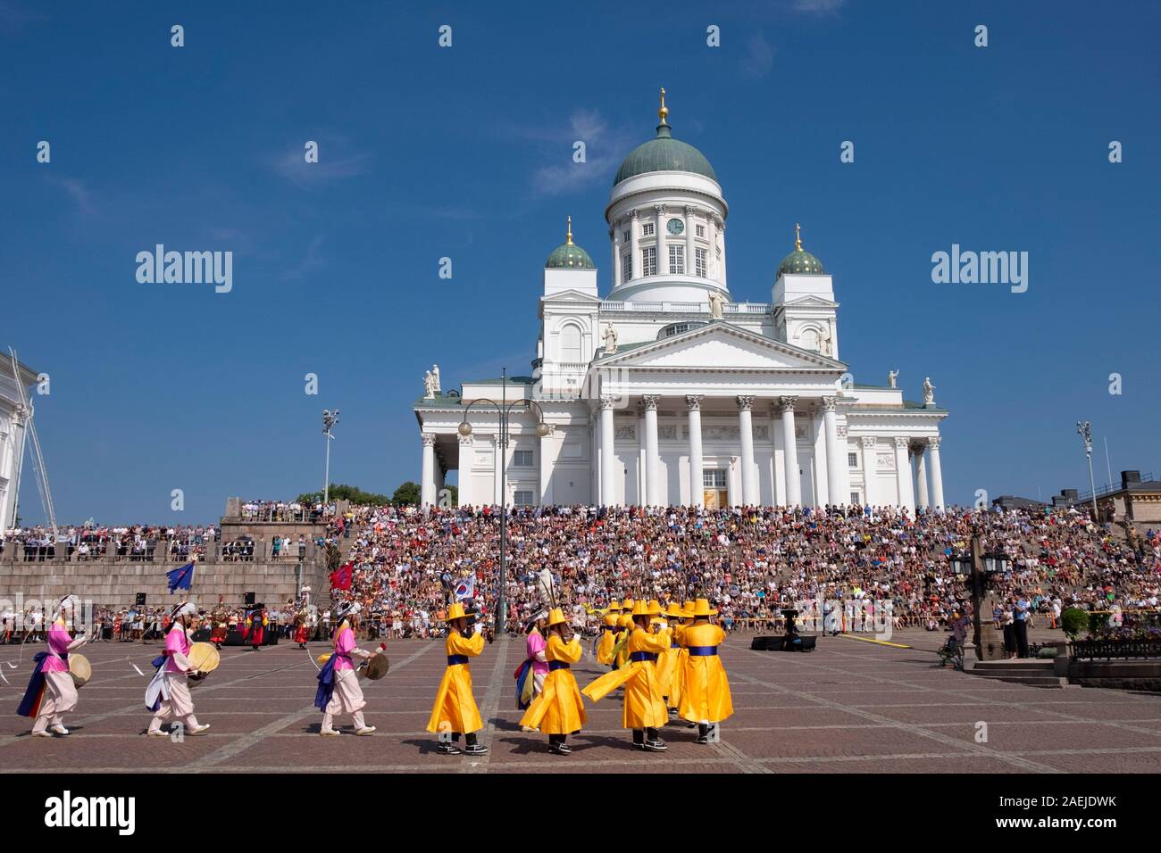 Vista su tutta la Piazza del Senato verso sud coreano banda militare e la gente seduta sui gradini della cattedrale luterana, Helsinki, Finlandia, Europa Foto Stock