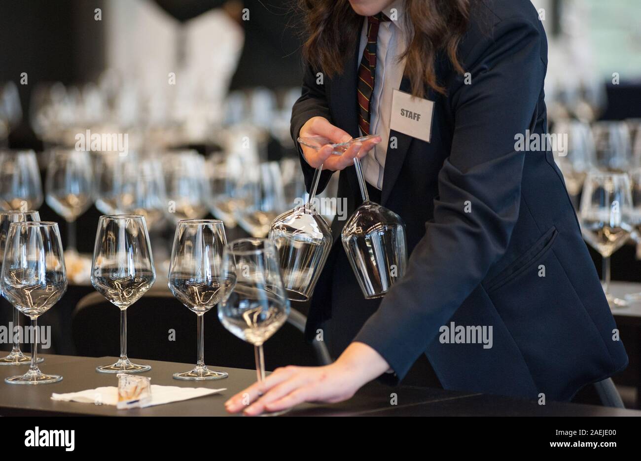Cameriera di impostare le tabelle con cristallo gobles per una degustazione di vino workshop. Il servizio di catering e il personale di sala a lavoro. Foto Stock