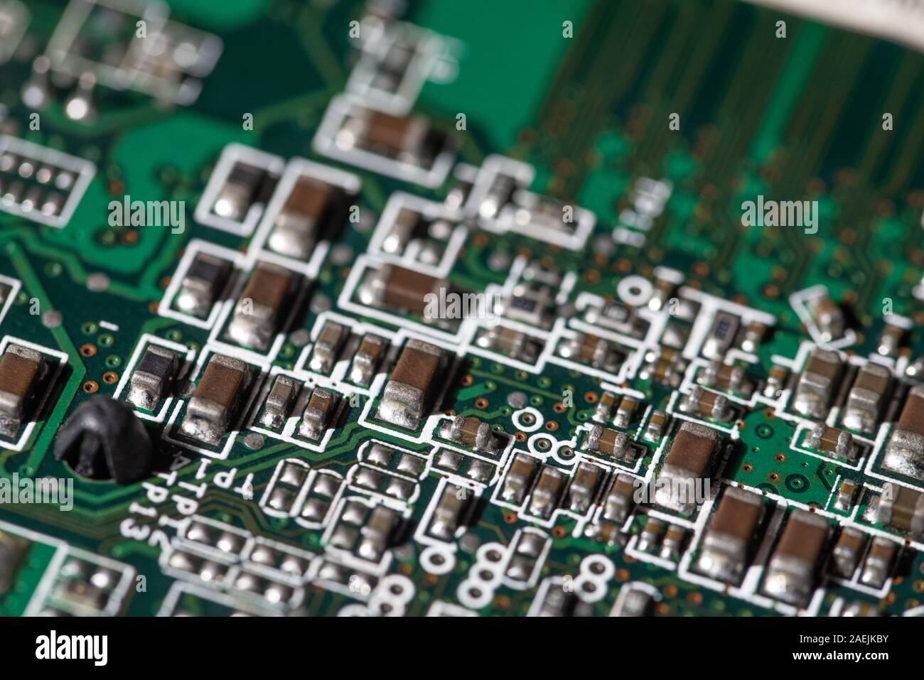 Vista dettagliata dei componenti elettronici su una scheda a circuito stampato verde utilizzata nei moderni dispositivi elettronici Foto Stock