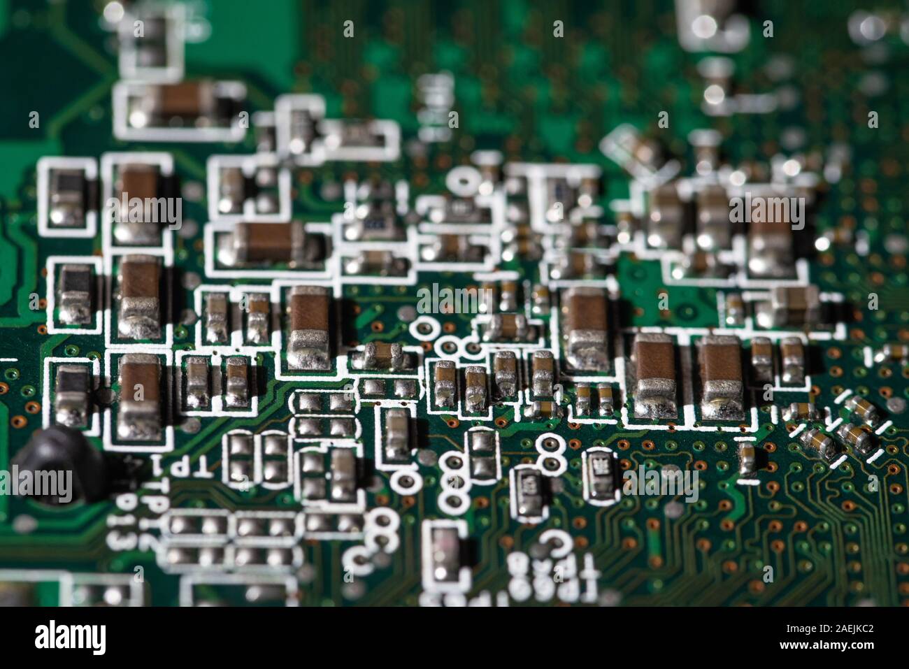 Vista dettagliata dei componenti elettronici su una scheda a circuito stampato verde utilizzata nei moderni dispositivi elettronici Foto Stock