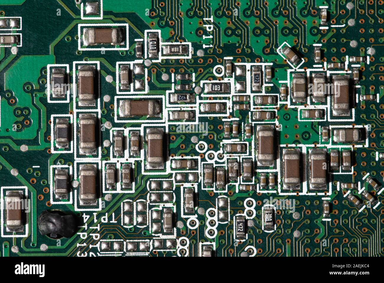 Vista dettagliata dei componenti elettronici su una scheda a circuito stampato verde utilizzata nei moderni dispositivi elettronici Foto Stock