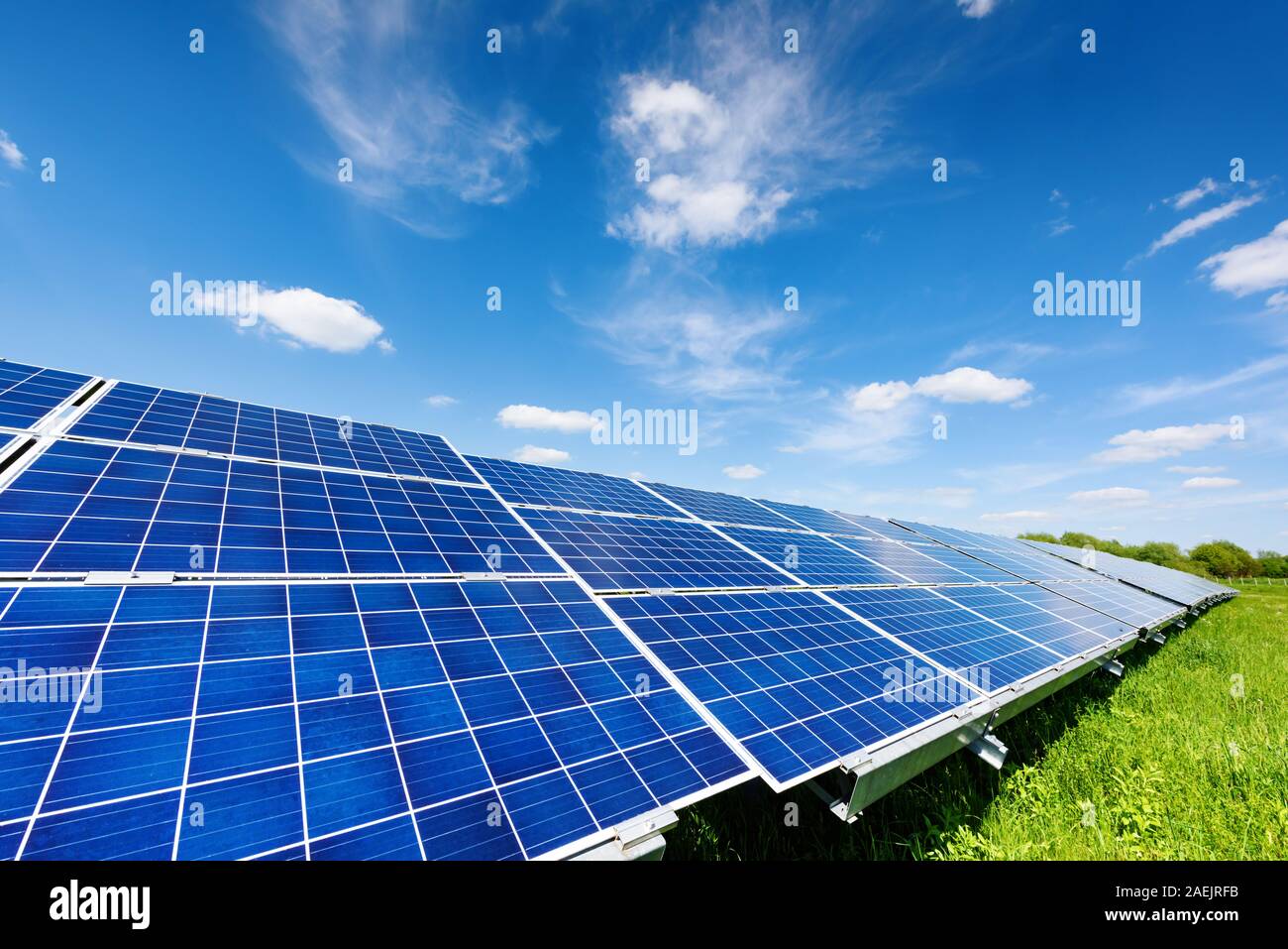 Pannello solare sul cielo blu sullo sfondo. Erba verde e cielo nuvoloso. L'energia alternativa nozione Foto Stock