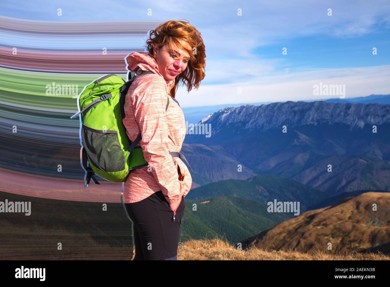 Ragazza di montagna con pixel stretch a Iezer-Papusa montagne, Romania, con i capelli al vento e un grande zaino verde. Concetto di escursionismo. Foto Stock