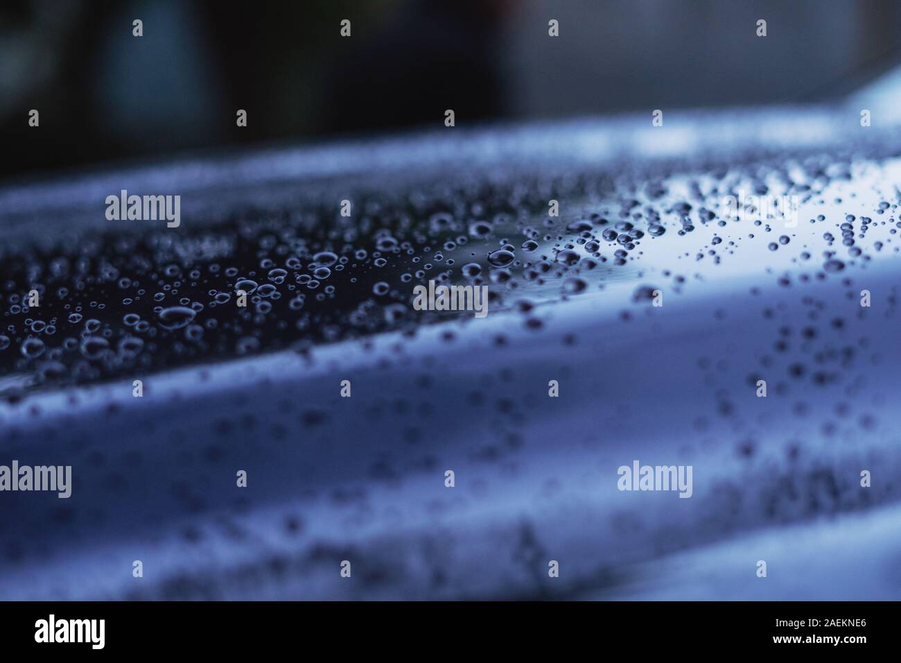 Gocce d'acqua sulla superficie di un auto blu in colori freddi Foto Stock