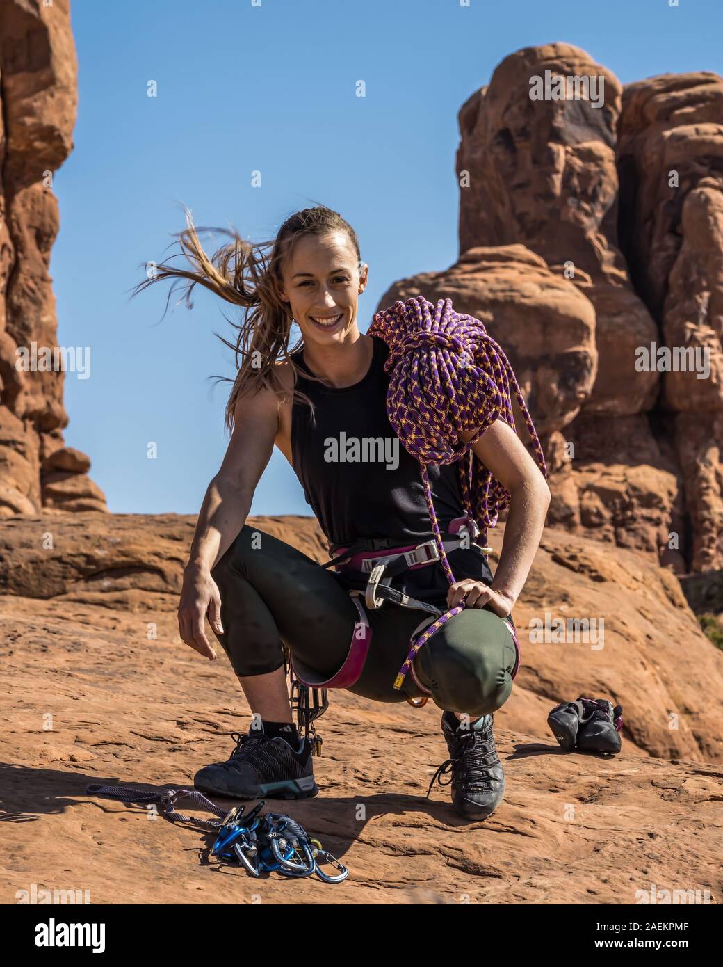 Un attraente giovane donna pone con la sua scalata marcia nel giardino di Eden nel Parco Nazionale di Arches nei pressi di Moab, Utah. Foto Stock