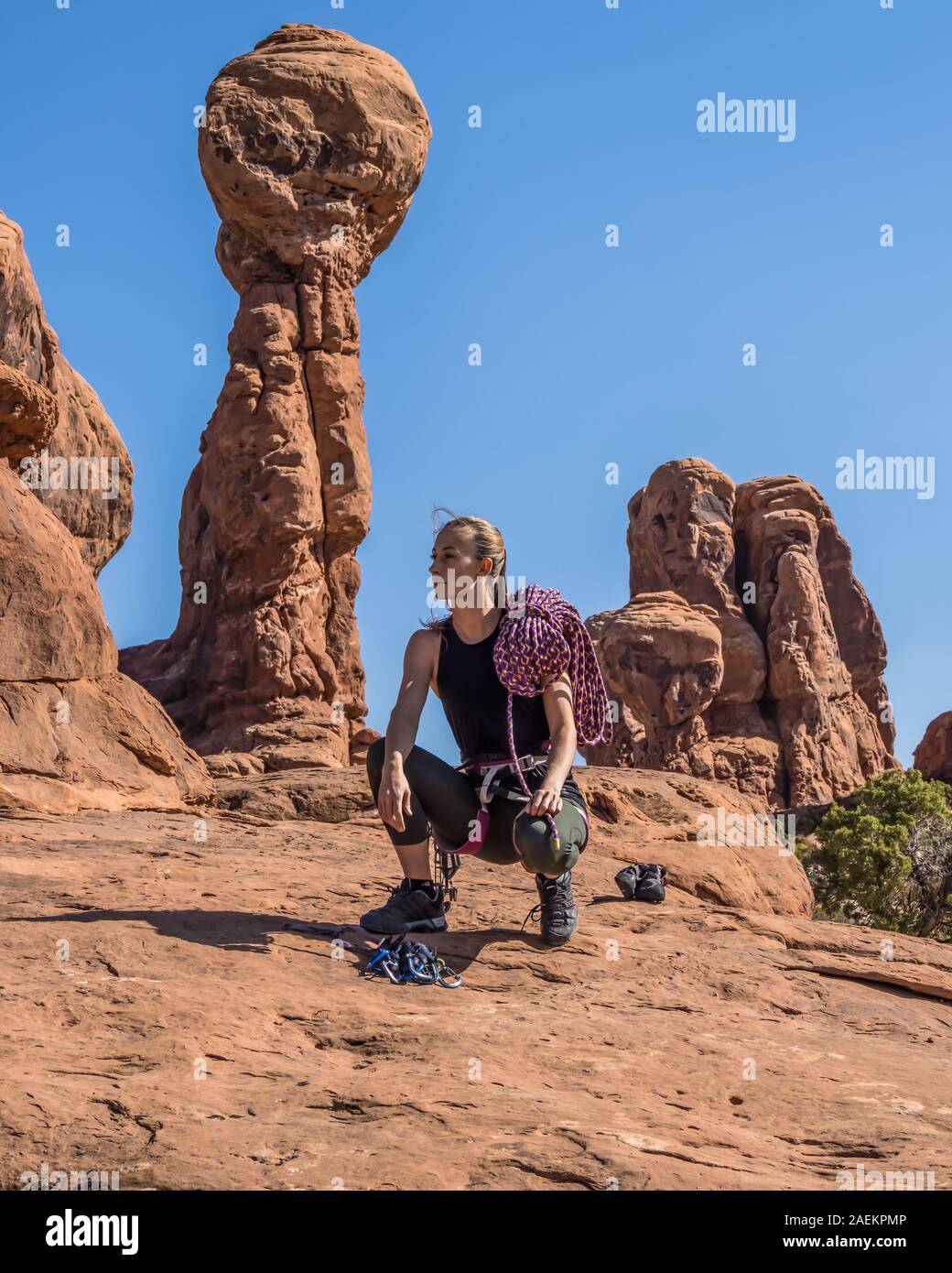 Un attraente giovane donna pone con la sua scalata marcia nel giardino di Eden nel Parco Nazionale di Arches nei pressi di Moab, Utah. Foto Stock