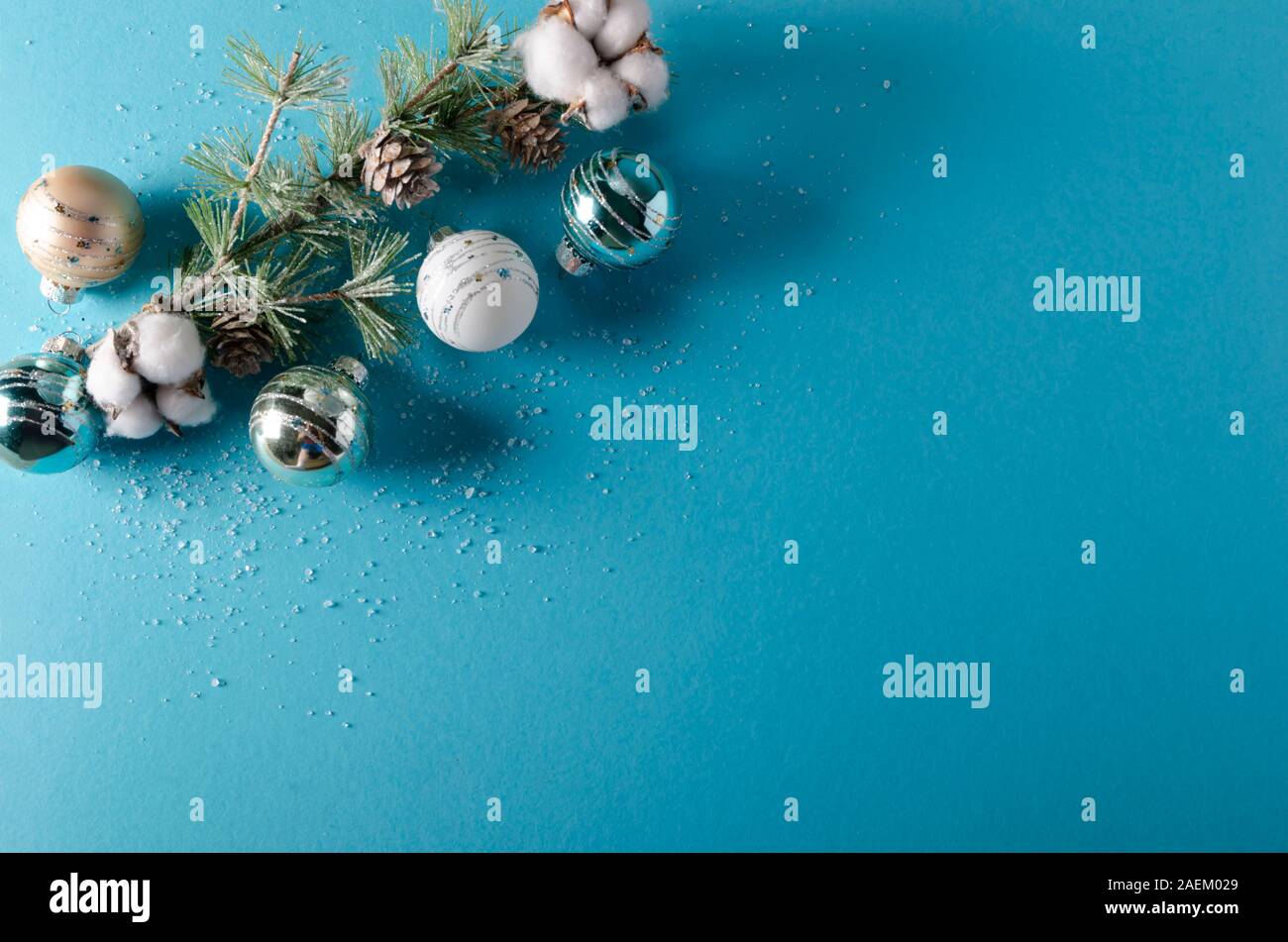 Composizione da tavolo natalizia in studio con ornamenti, vegetazione, accenti di cotone, effetto neve e spazio per il testo su sfondo blu foglia di tè. Foto Stock