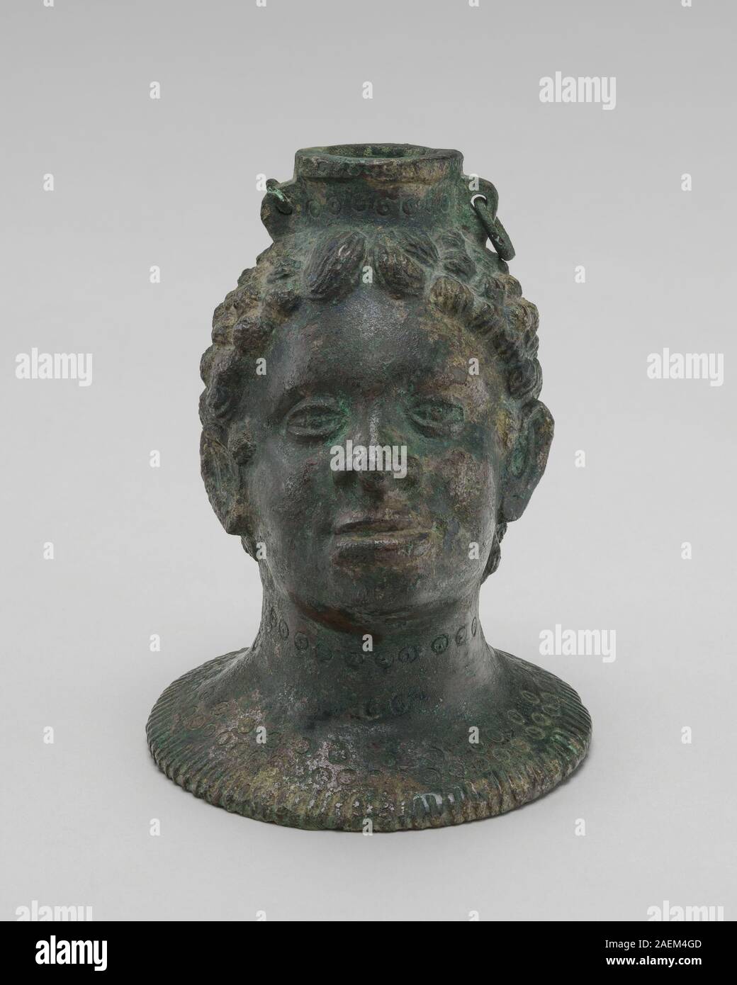 Questo contenitore etrusco del IV-II secolo a.C. ha la forma di una testa africana, caratterizzato da una costruzione in ceramica, una modellazione facciale dettagliata e un uso funzionale come nave. Foto Stock