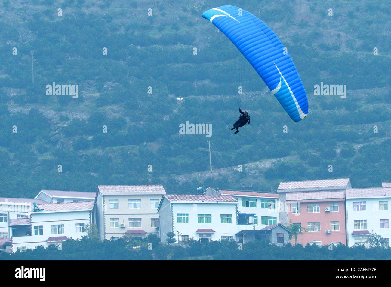 Un pilota di parapendio esegue stunt battenti in Zigui county, Yichang city, centrale cinese della provincia di Hubei, 9 novembre 2019. Foto Stock