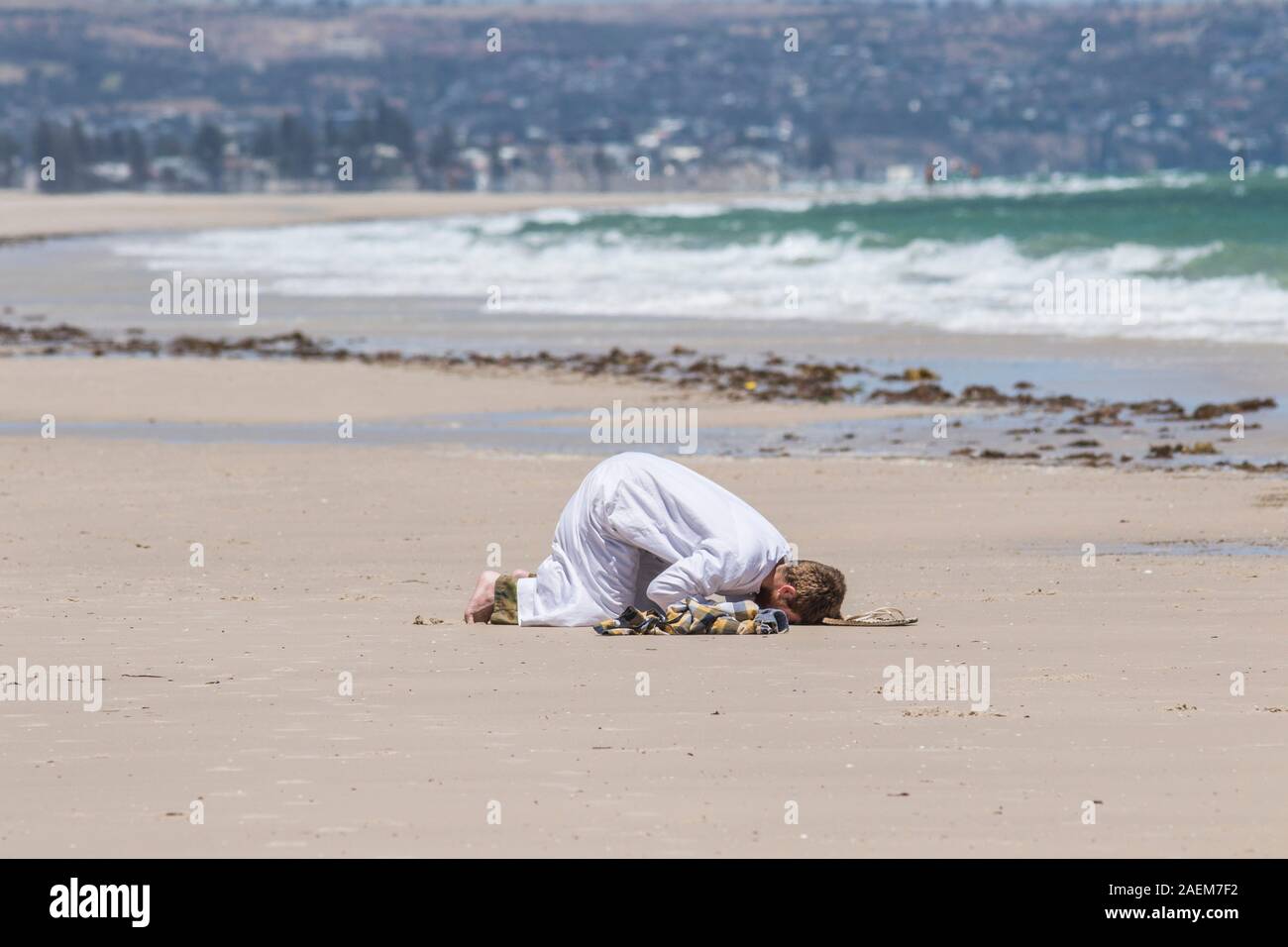 Adelaide, Australia il 10 dicembre 2019 .Un uomo compie il rito islamico Salat Al Zuhr come si prostra in preghiera sulla sabbia a una spiaggia a mezzogiorno sotto la sfolgorante sole caldo di Adelaide. Credito: amer ghazzal/Alamy Live News Foto Stock