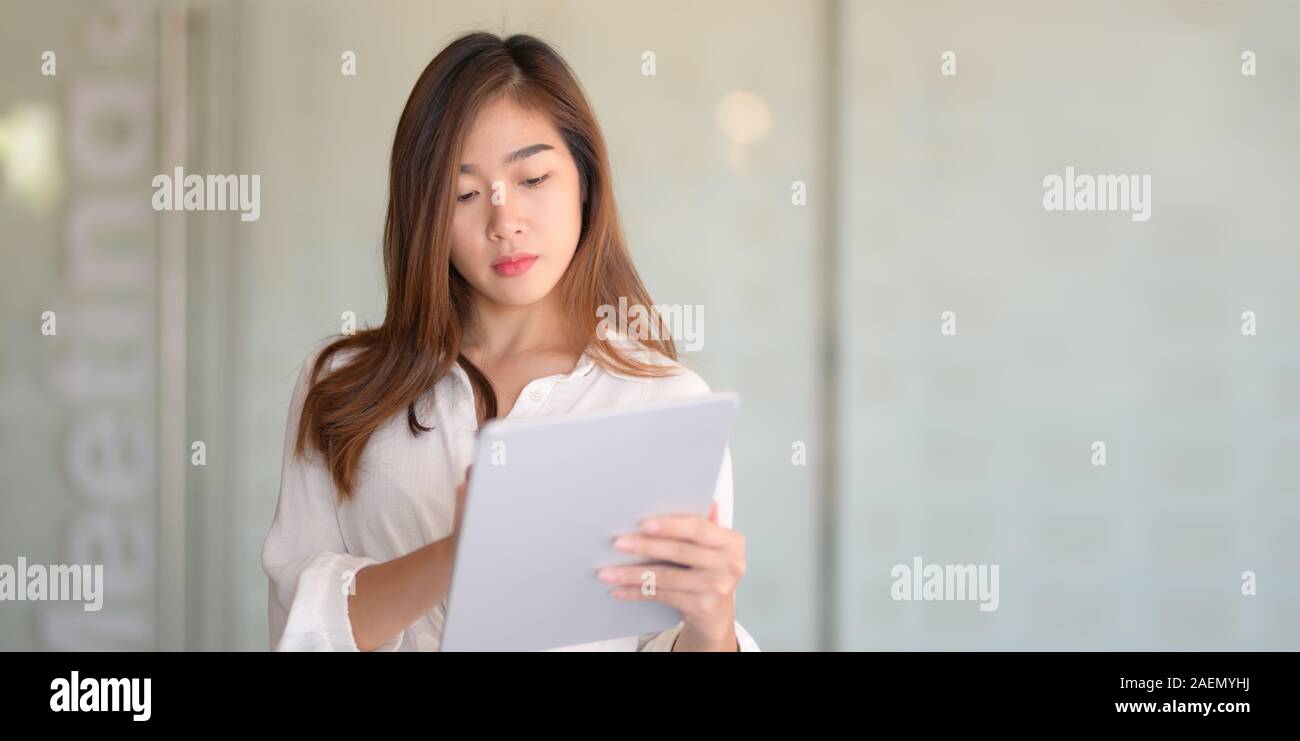 Ritratto di giovane bella imprenditrice la lettura di documenti aziendali in ufficio moderno camera Foto Stock