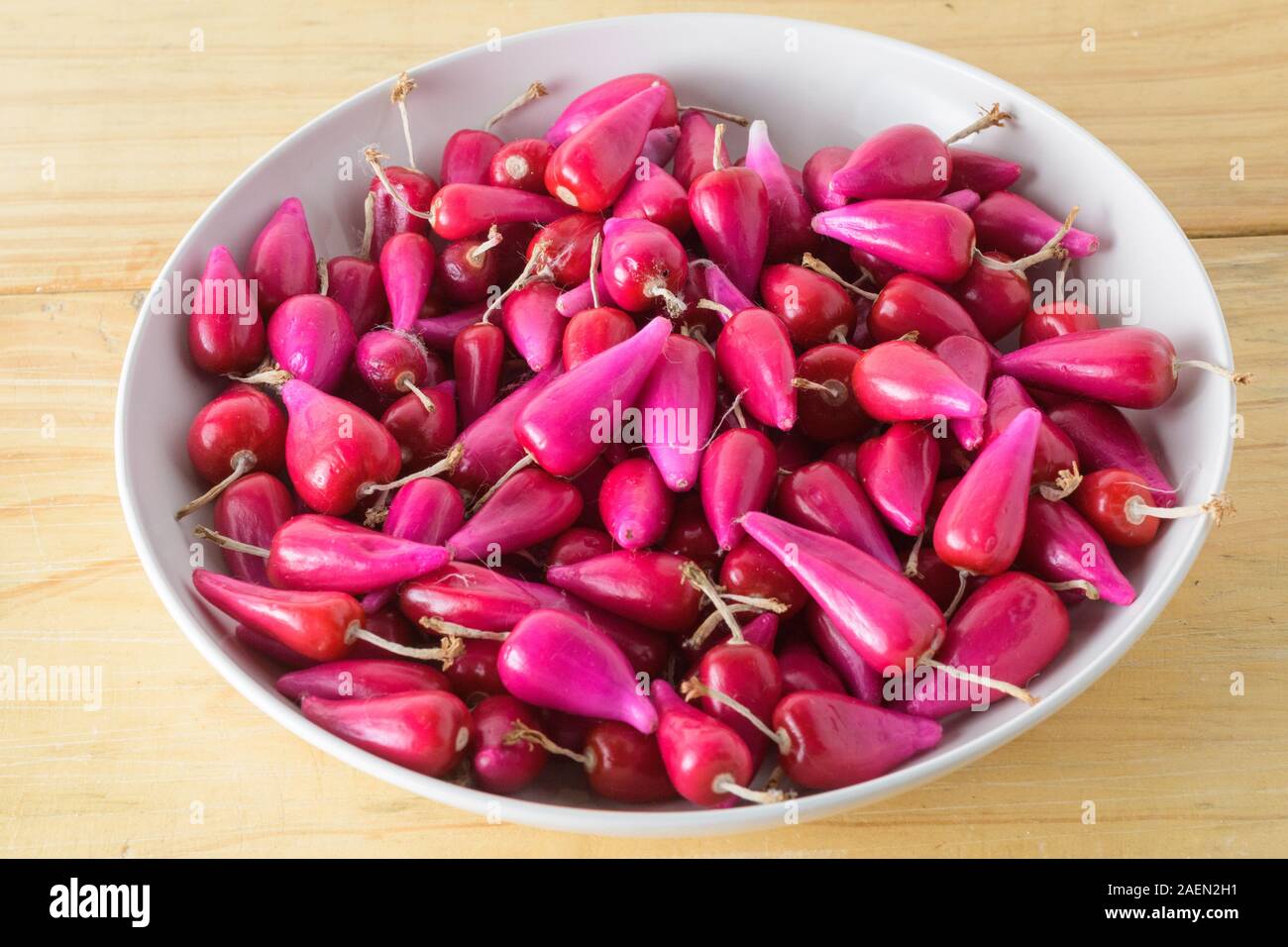 Gruppo di frutta rosa Pitiguey fresca in ciotola bianca su tavola di legno. Foto Stock