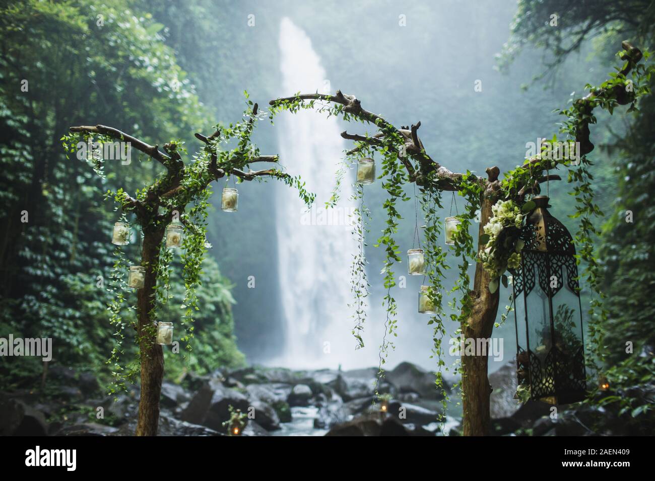 Cerimonia di nozze su enorme cascata Nung Nung in Bali, Indonesia jungle. Arch a secco con rami di legno e verde edera. Destinazione insolita per un matrimonio. Foto Stock