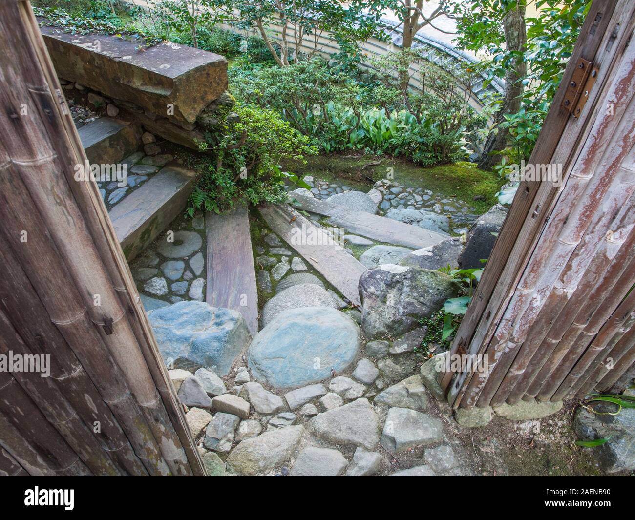 Guardando attraverso il gateway di bambù, una curva in pietra approccio percorso via di porta di ingresso, Tile parete superiore al di sotto, Garyusanso, Ozu, Ehime Shikoku Giappone Foto Stock
