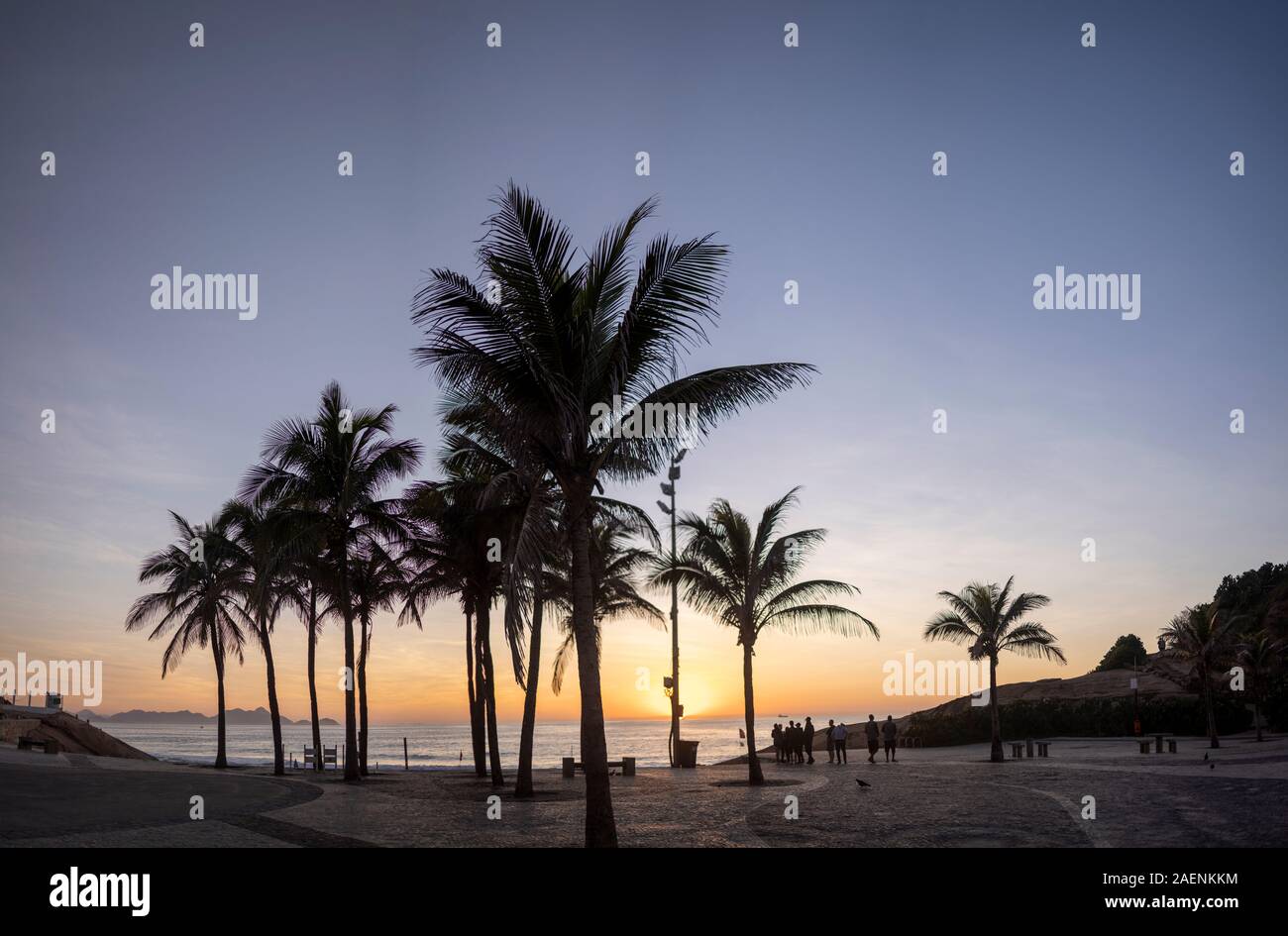 Alba sul Arpoador boulevard con la spiaggia di diavoli e stagliano palme a Rio de Janeiro contro un arancione chiaro e blu cielo Foto Stock