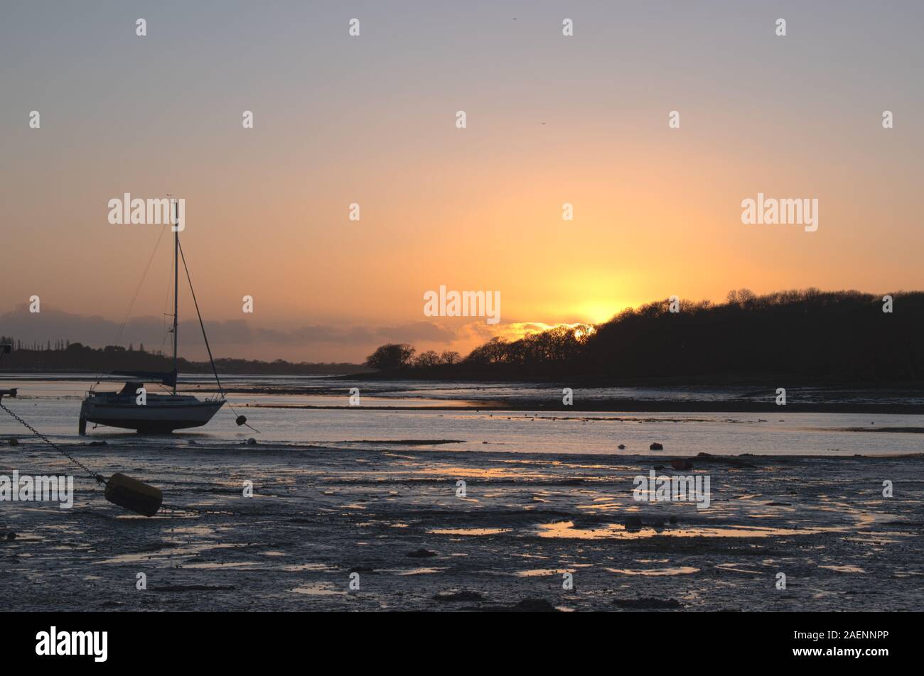 Tramonto a Dell Quay sailing club nelle vicinanze del Chichester. Sun appena oltre l'orizzonte impostazione in un tripudio di colori e la riflessione dell'acqua e sabbia. Foto Stock
