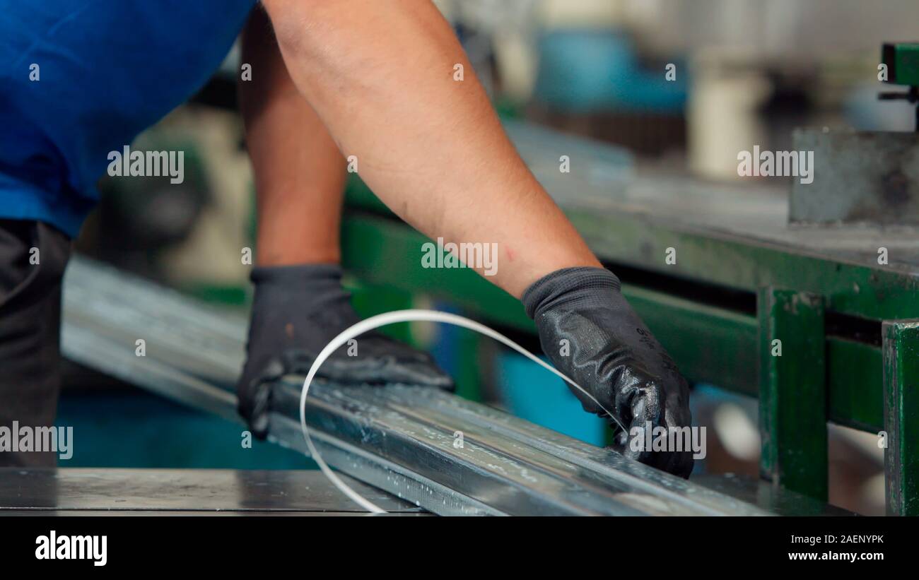 Operaio di fabbrica di imballare il metallo profili in alluminio con nastro di imballaggio nel processo di fabbricazione di carpenteria industriale impianto. La protezione del prodotto per Foto Stock