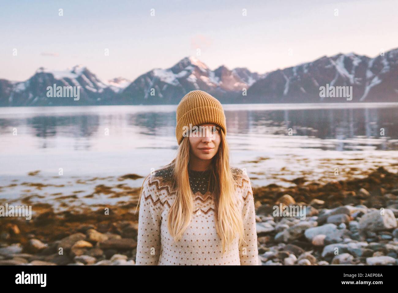 Giovane donna all'aperto Viaggi Vacanze avventura in Norvegia il tramonto sulle montagne e il paesaggio del fiordo capelli biondi scandinavian ragazza maglione accogliente e lavorati a maglia Foto Stock
