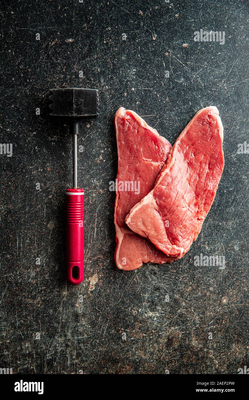 Raw cotoletta di vitello. Carne e un mazzuolo. Vista dall'alto. Foto Stock