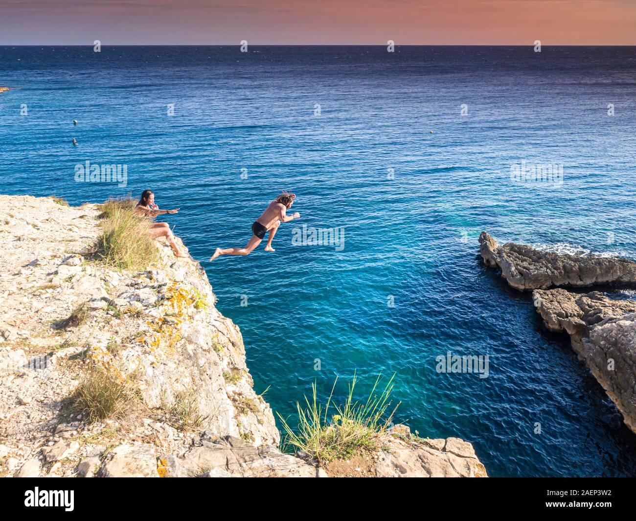 Croazia, Istria, Pola, Cape Kamenjak, uomo saltare da una scogliera Foto Stock