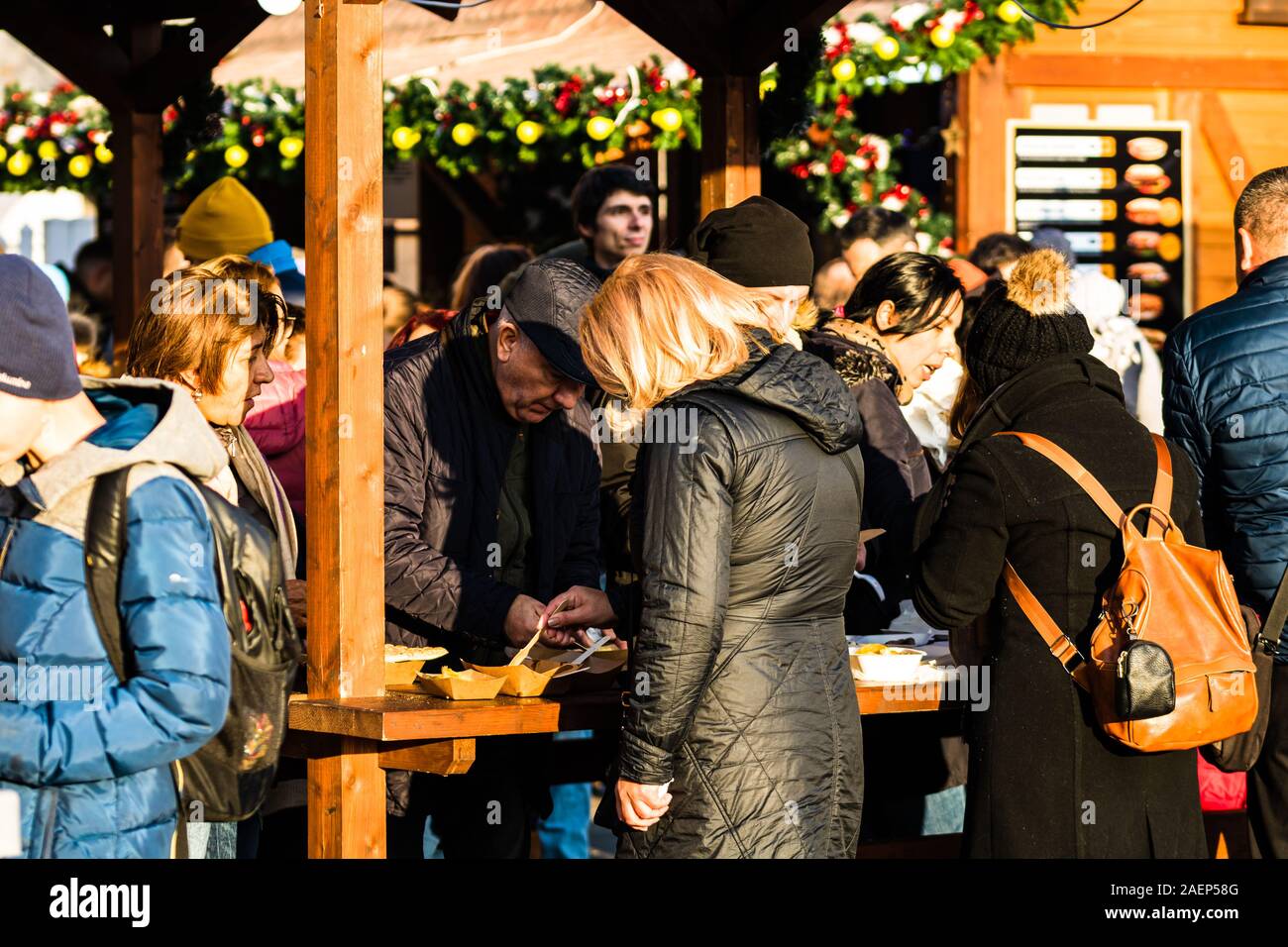 Le persone aventi il pranzo con il rumeno tradizionale cibo a Bucarest il mercatino di Natale. Bucarest, Romania, 2019. Foto Stock