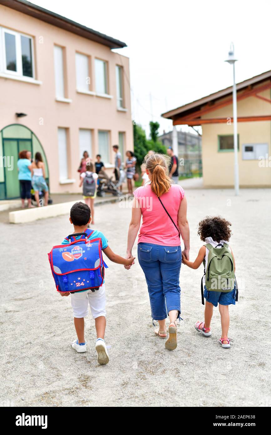 La Madre che accompagna i suoi due figli a scuola primaria Foto Stock