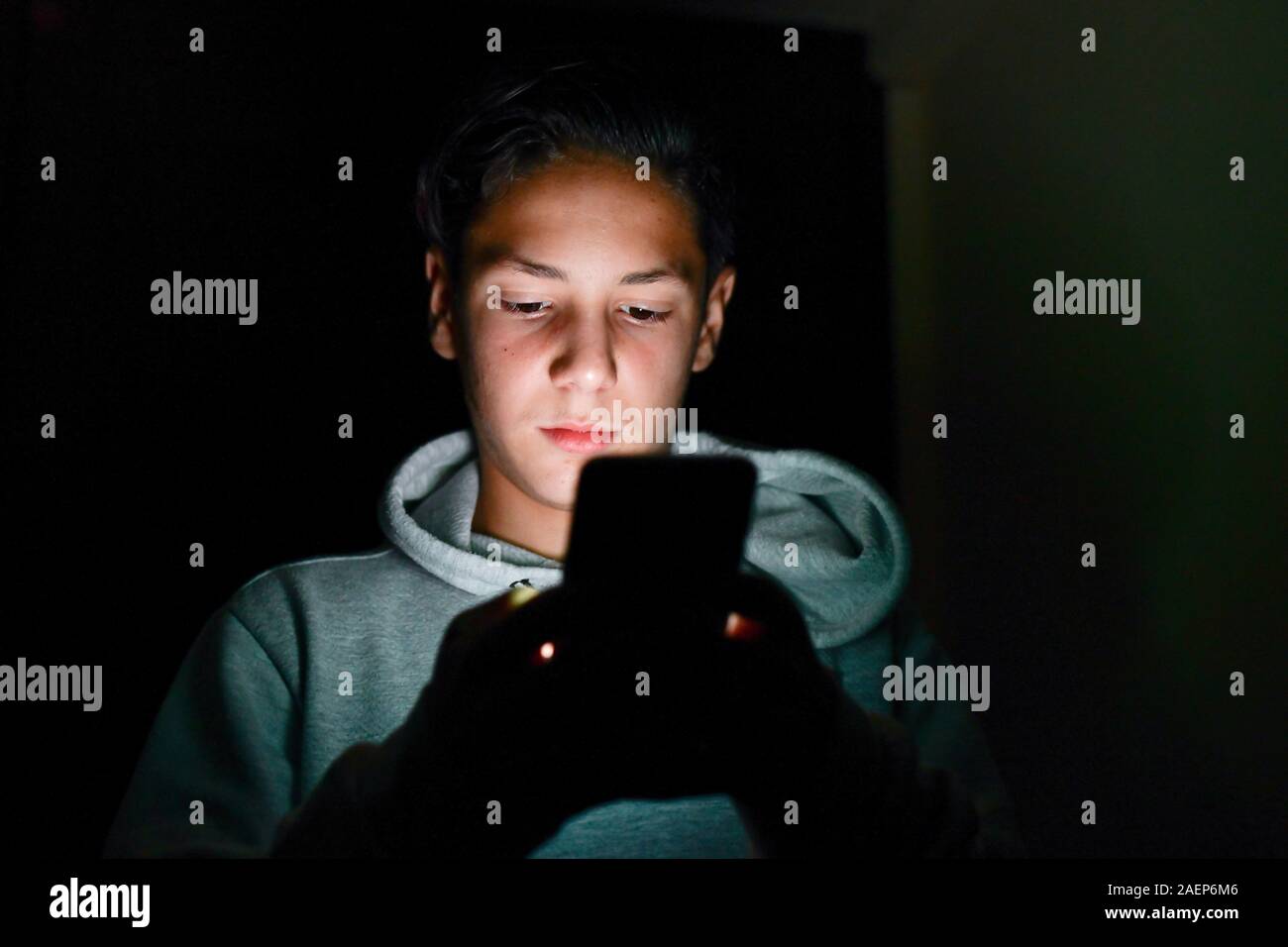 Adolescente utilizzando uno smartphone, invio di un messaggio. Adolescente utilizzando i suoi due pollici per scrivere un messaggio sulla tastiera del suo smartphone Foto Stock