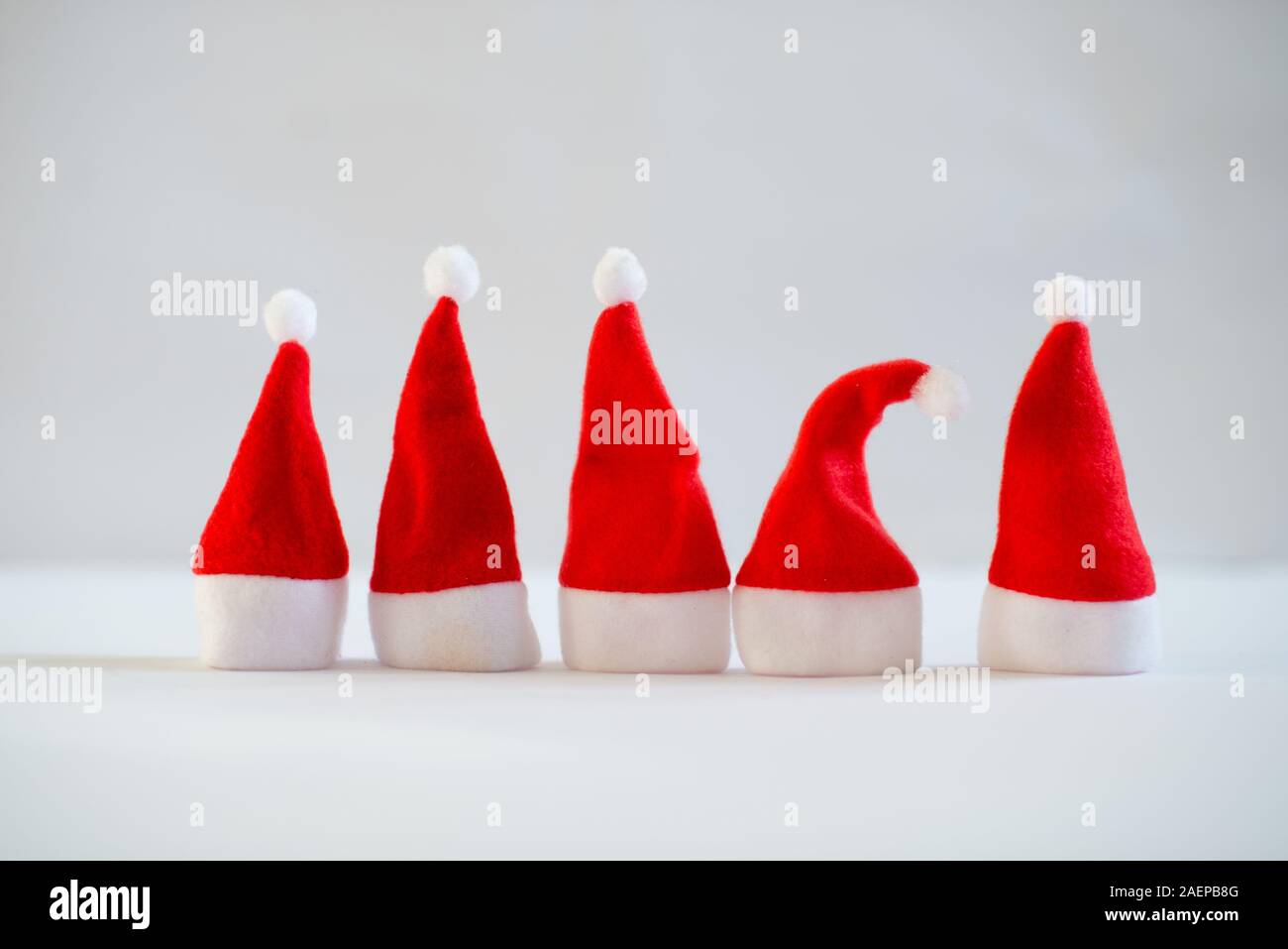 Dicembre con piccoli cappelli di Babbo Natale su sfondo bianco. Sfondo di natale, spazio di copia Foto Stock