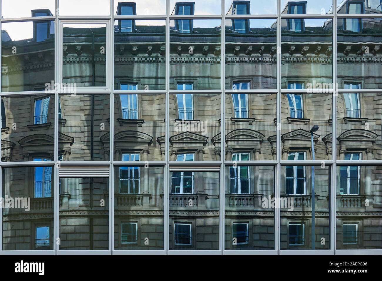 La riflessione di una facciata storica del periodo guglielmino nel moderno ed austera, la parte anteriore in vetro di un edificio alto Foto Stock