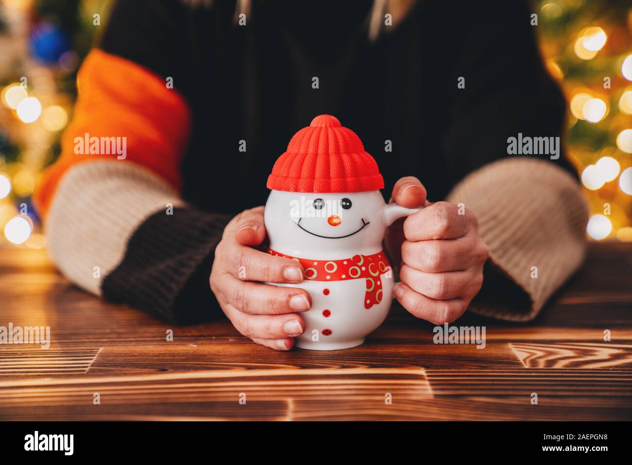 Giovane donna è seduto in un bar e drink con un pupazzo di neve cup. Concetto di natale. Foto Stock