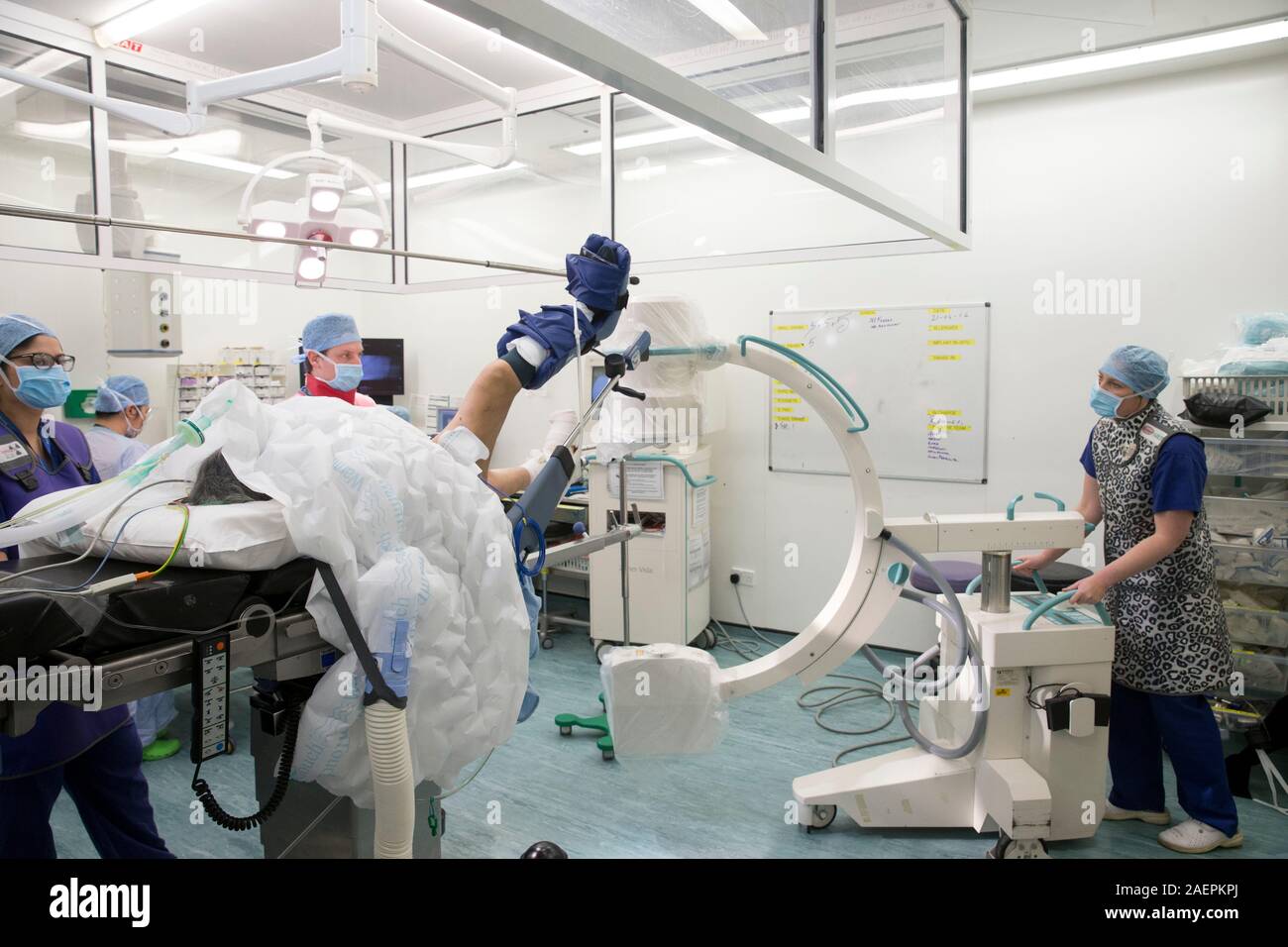 Tre infermieri in frega in un teatro ospedaliero preparare un paziente per la chirurgia della caviglia Foto Stock