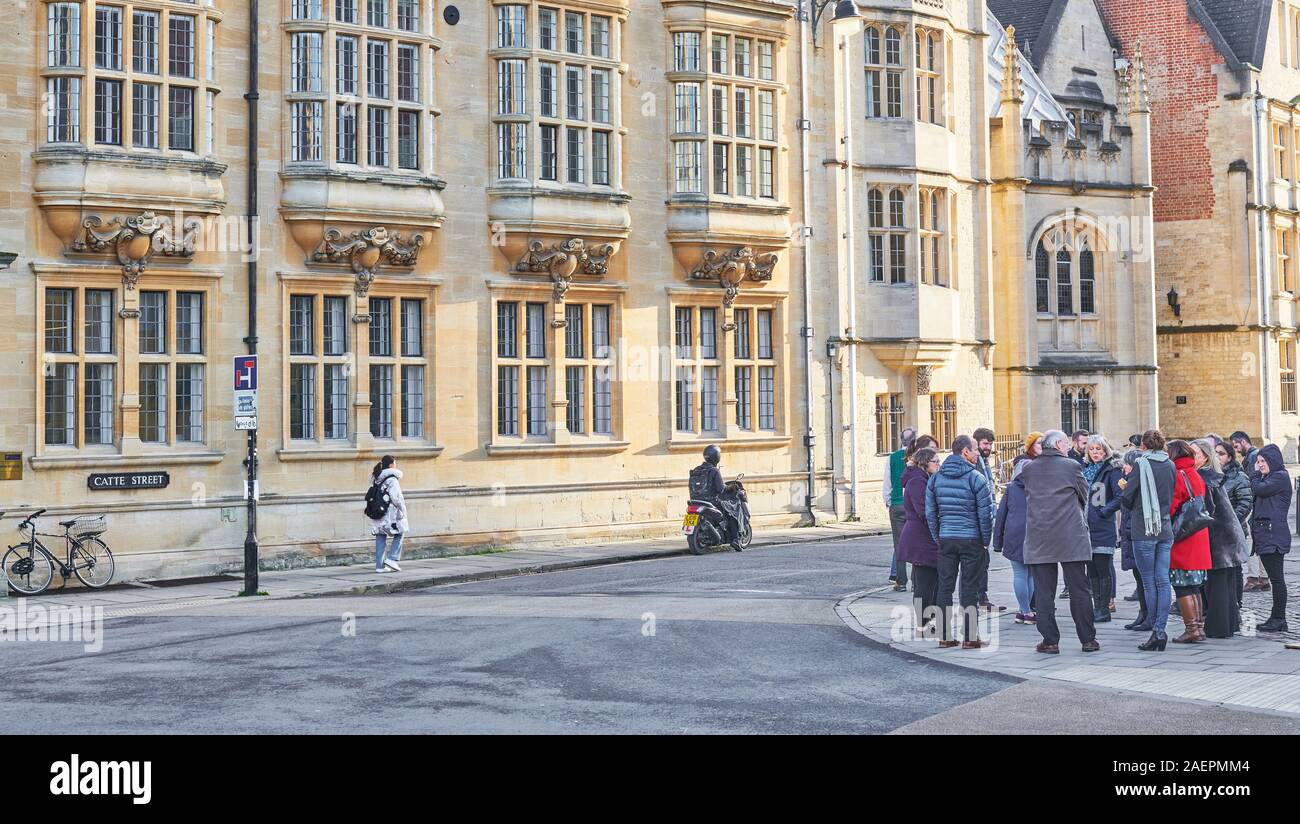 Un gruppo turistico sorge al di fuori dell'edificio Clarendon, biblioteca Bodleian, Università di Oxford, Inghilterra, opposta Hertford College, in un freddo inverno, d Foto Stock