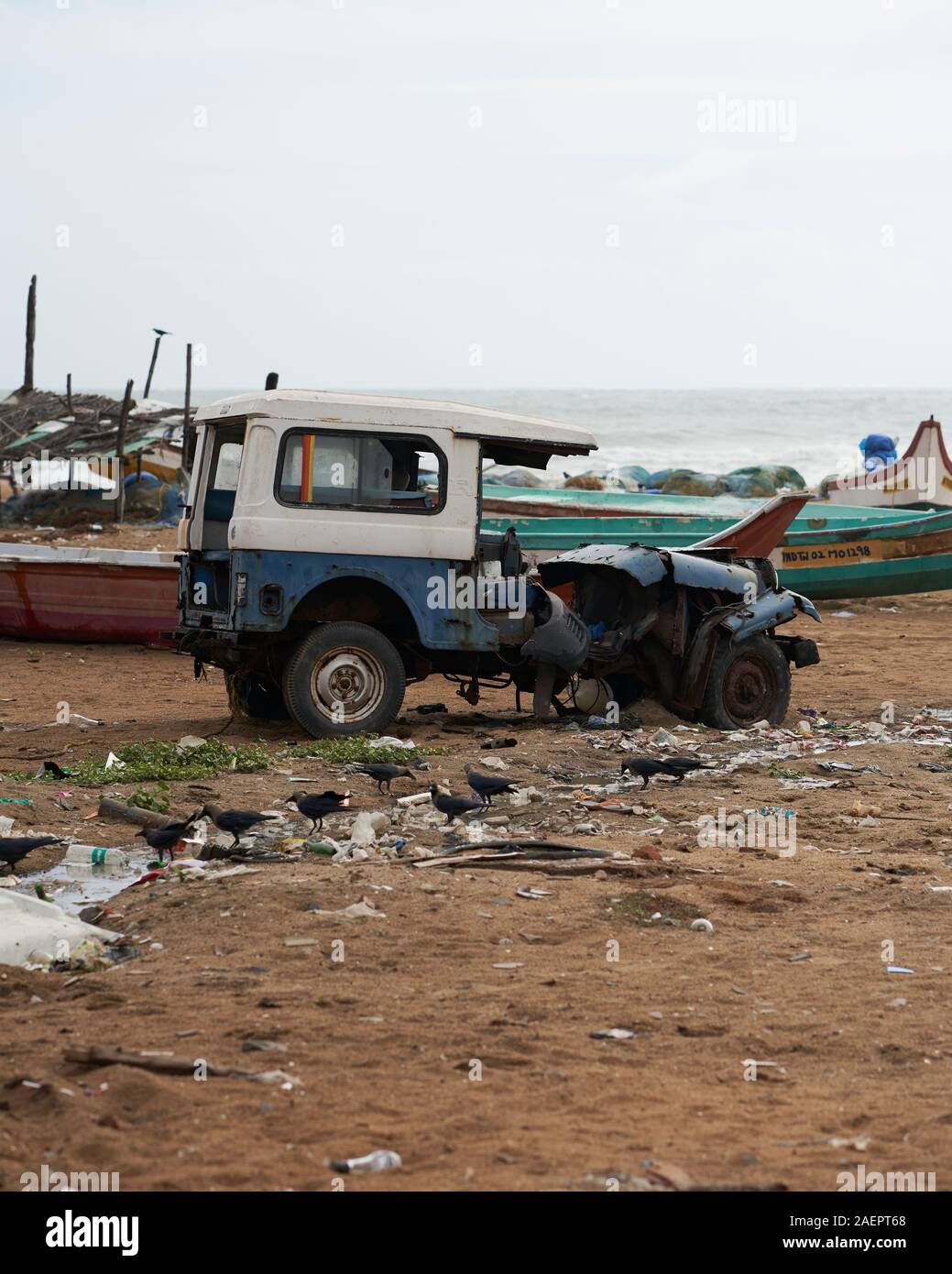 Un veicolo abdoneded Elliots sulla spiaggia circondata da barche da pesca e cestino Foto Stock