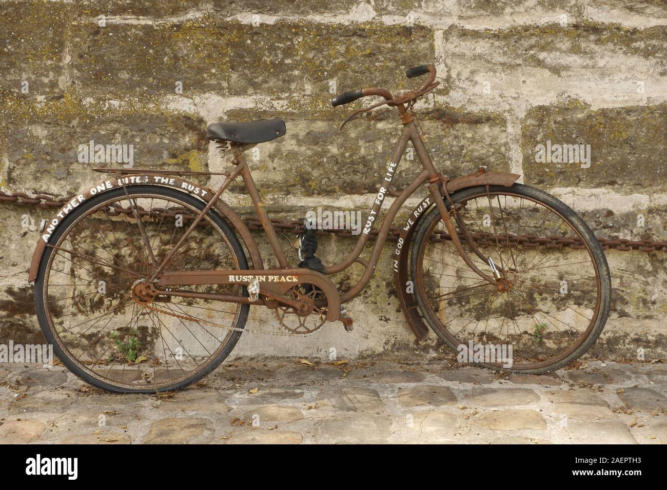 Una vecchia bicicletta arrugginita incatenato ad una parete a Parigi.la  ruggine in pace in scritti sul lato di essa Foto stock - Alamy