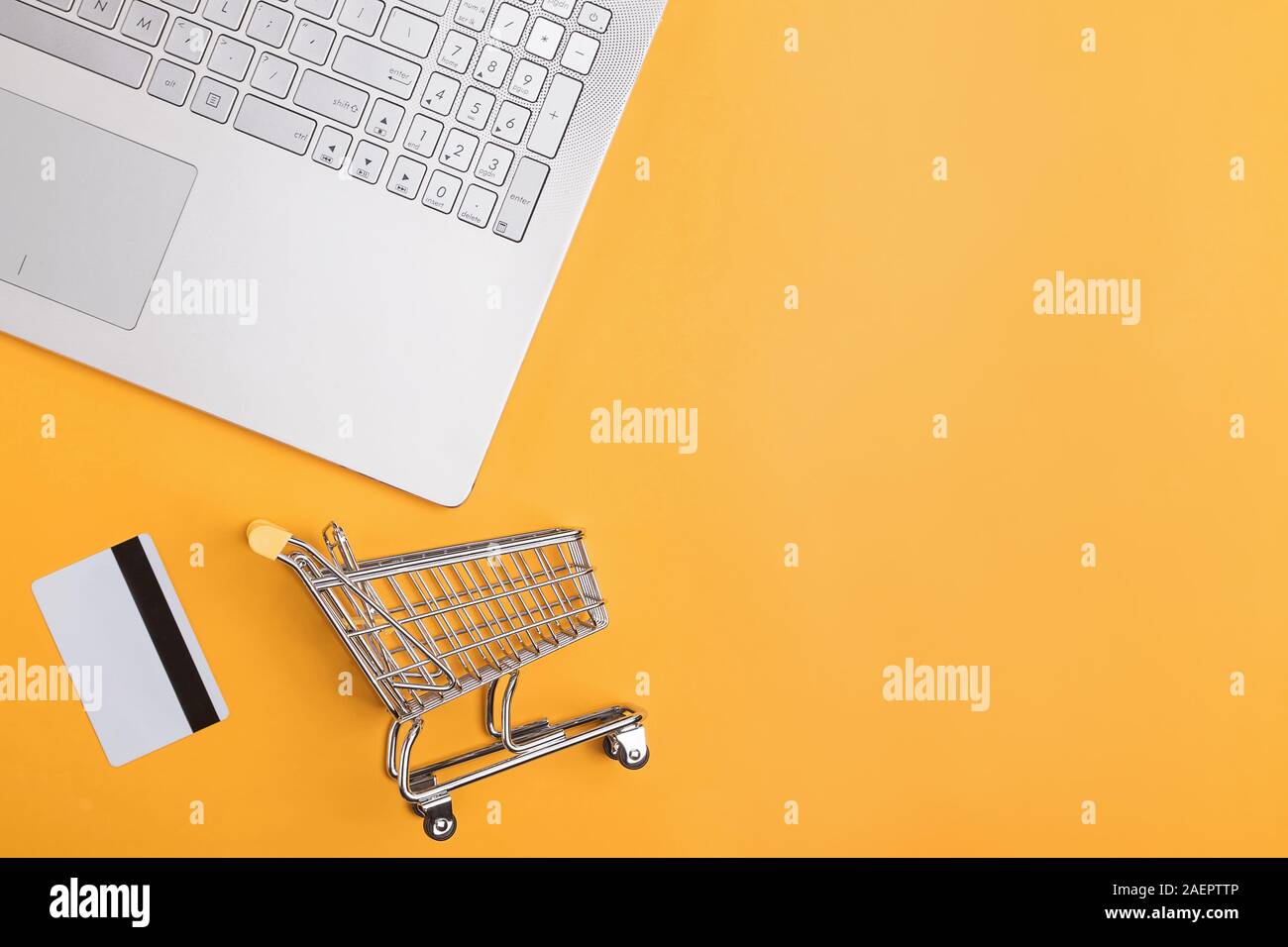 Laptop, carte di credito e piccoli carrello di shopping su sfondo giallo Foto Stock