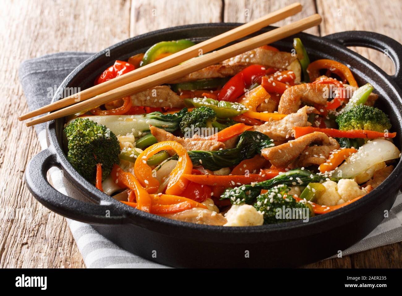 Mescolare sano maiale fritto con diversi ortaggi close-up in una padella sul tavolo orizzontale. Foto Stock