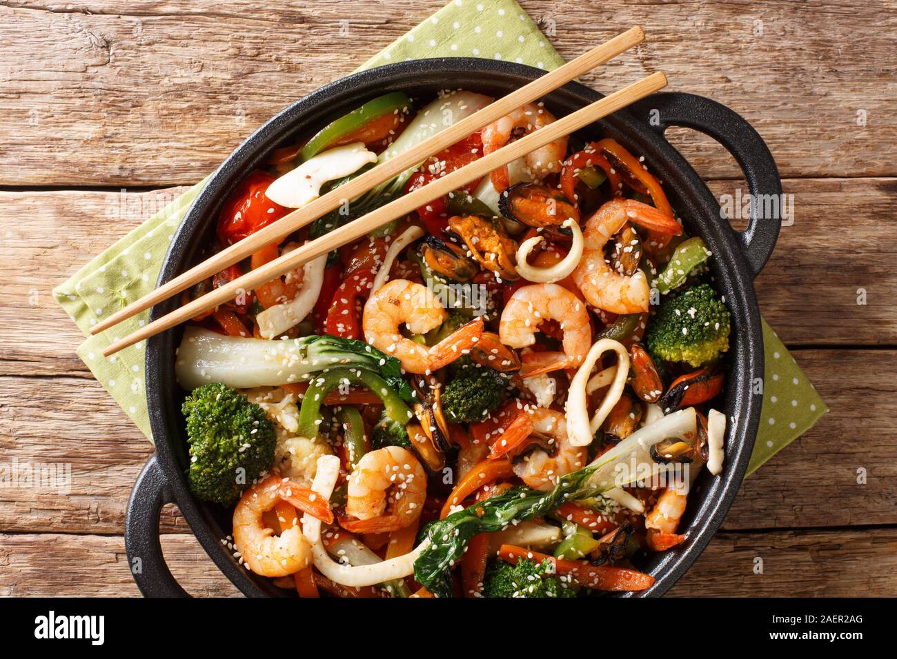 Una pentola mescolare gamberi fritti, calamari e cozze con fresche verdure di stagione di close-up in una padella sul tavolo. Parte superiore orizzontale vista da sopra Foto Stock