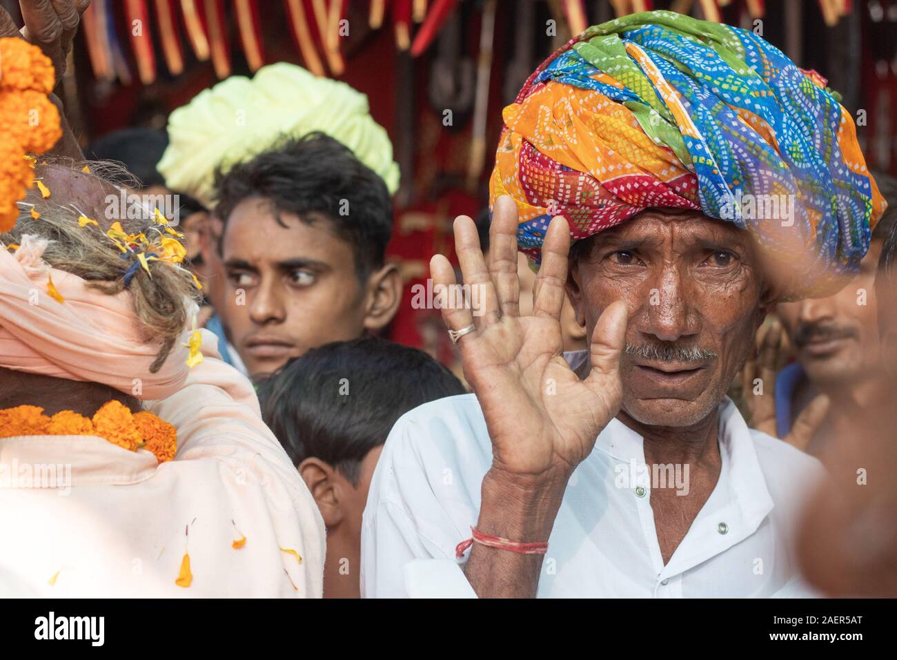 Rajasthani povero vecchio ragazzo tessitura di mani verso di rally indossando turbante colorato Foto Stock