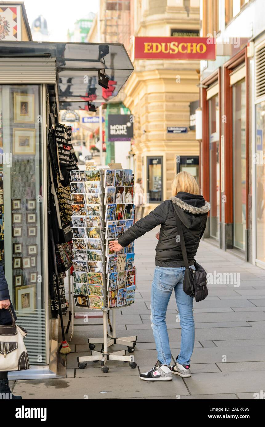 Donna che guarda le cartoline sul Graben San, città vecchia strada principale di Vienna, Austria. Foto Stock