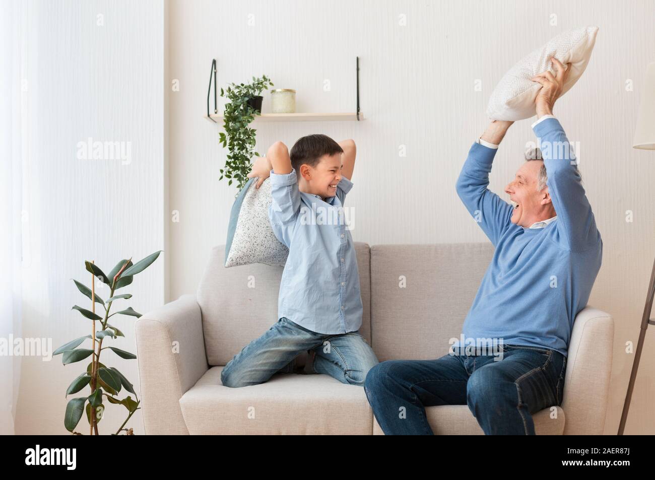 Ragazzo e nonno in lotta con i cuscini sul lettino a casa Foto Stock