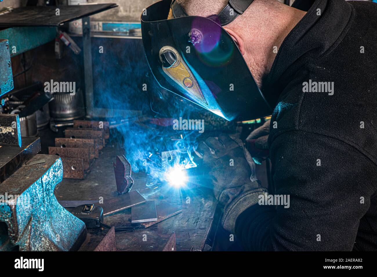 Saldatura elettrica processo. Lavoratore nella maschera di saldatura. Bianco brillante e blu. Foto Stock