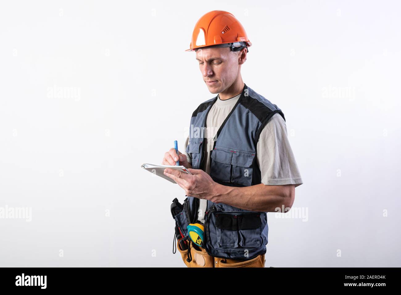 Builder con un blocco note. In un casco e un accappatoio. Scrive i dati. Foto Stock